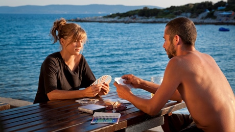 Two people playing cards at a table by the sea