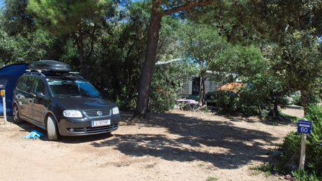 Een auto geparkeerd op een camping omringd door bomen