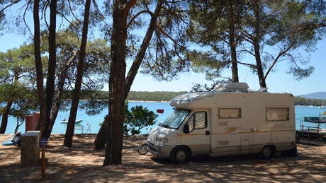 Een camper geparkeerd in een bosrijk gebied nabij een meer