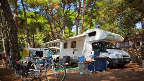 Camper en fiets geparkeerd op een beboste camping