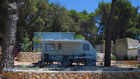 Caravan omgeven door bomen op een camping