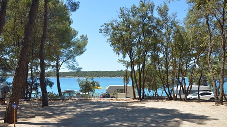 Een schilderachtig uitzicht op een camping nabij een bos en een blauw meer