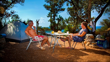 Buitencampingopstelling met twee mensen die aan een tafel zitten en van een maaltijd genieten