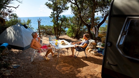 Mensen ontspannen op een camping bij de zee met een tent en camper