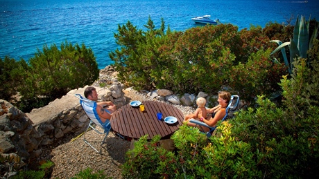 Gezin geniet van een maaltijd aan een tafel met een schilderachtig uitzicht op de oceaan