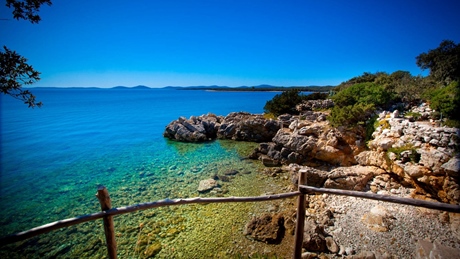 Scenic view of rocky shoreline and blue sea under a clear sky