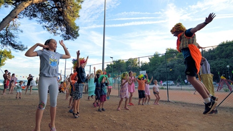 Children participating in a lively outdoor activity with a performer