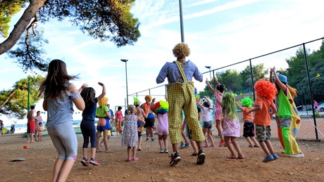 A group of children and a clown engage in outdoor activities at a park