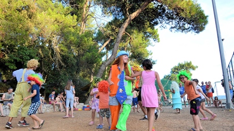 Clowns entertaining children outdoors during a fun event surrounded by trees