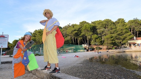 Two people dressed as clowns standing by a beach