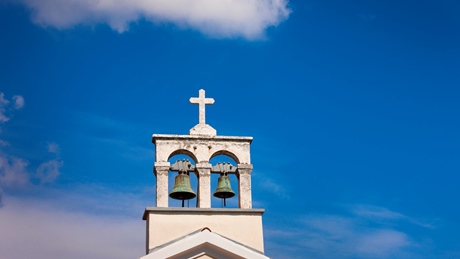 Church bell tower with a cross under a blue sky