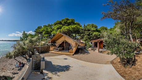 Product image of a glamping site with a tent and a scenic seaside view