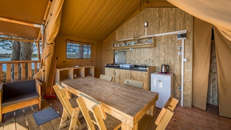 Interior of a rustic glamping tent with a dining table and kitchenette