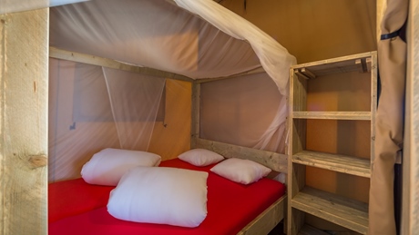 Cozy cabin interior with a wooden bed featuring red bedding and white pillows