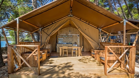 Safari-style glamping tent with outdoor seating in a forested area