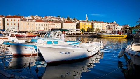 Boats docked in the harbor of Mali Losinj with colorful buildings in the background