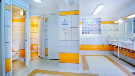 Moderne badkamer met wit-oranje betegelde muren, met toiletten en wastafels