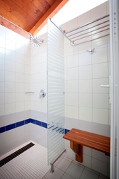 Moderne douche met glazen deur en houten bankje