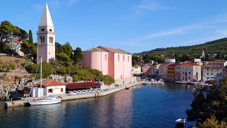 Scenic view of the waterfront in Losinj with a church and colorful buildings by the sea