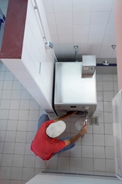 Een persoon in een rood shirt en pet werkt aan een roestvrijstalen machine