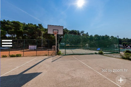 Basketball court next to a beach volleyball area under a clear sky