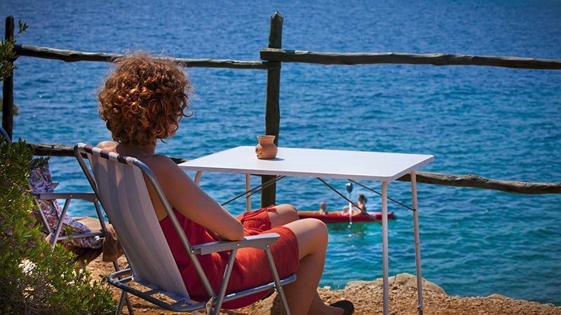 A woman sitting at a table overlooking the sea
