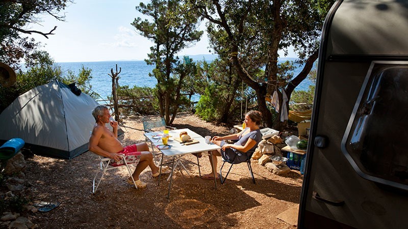 Two people relaxing at a campsite by the sea