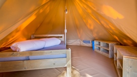 Interieur van een Baldarin-glamping-tent met een bed en planken