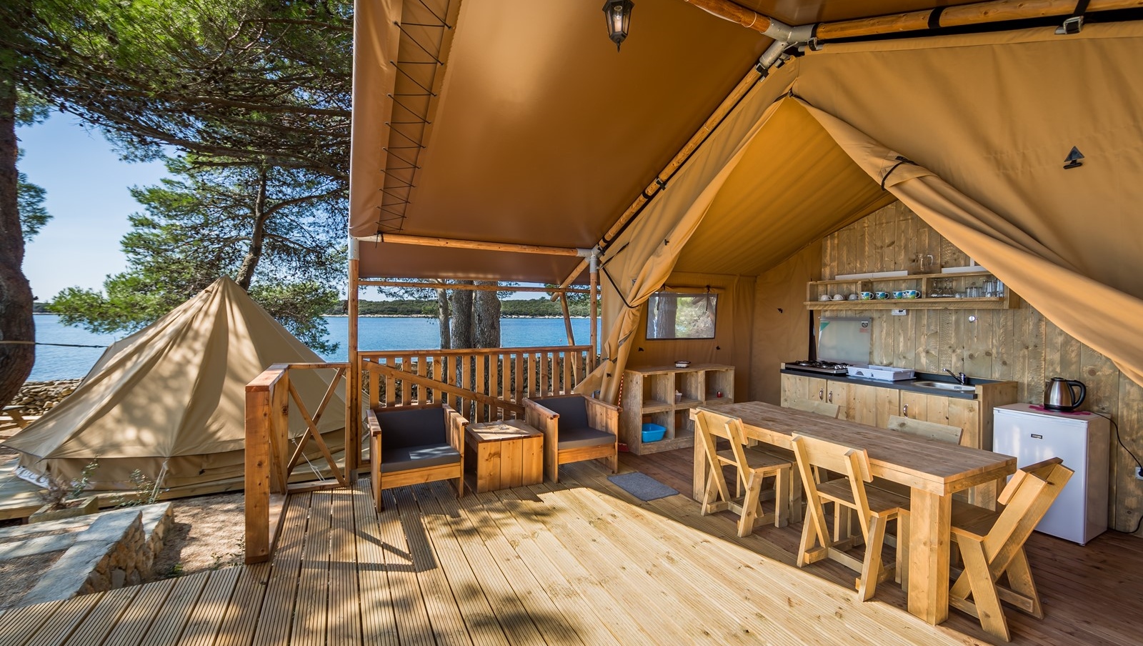 Outdoor glamping-opstelling bij Baldarin met houten terras, tent en zitgedeelte nabij de zee