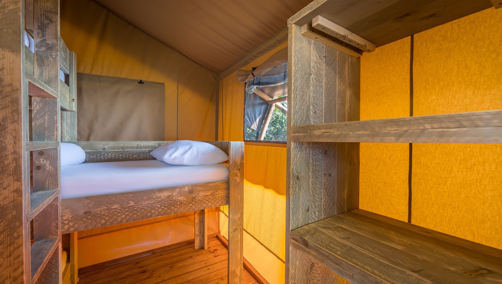 Interno di una tenda glamping con letti a castello in legno a Baldarin