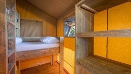 Interieur van een glamping tent met houten stapelbedden bij Baldarin