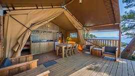 Baldarin glamping tent met houten interieur en uitzicht op de oceaan