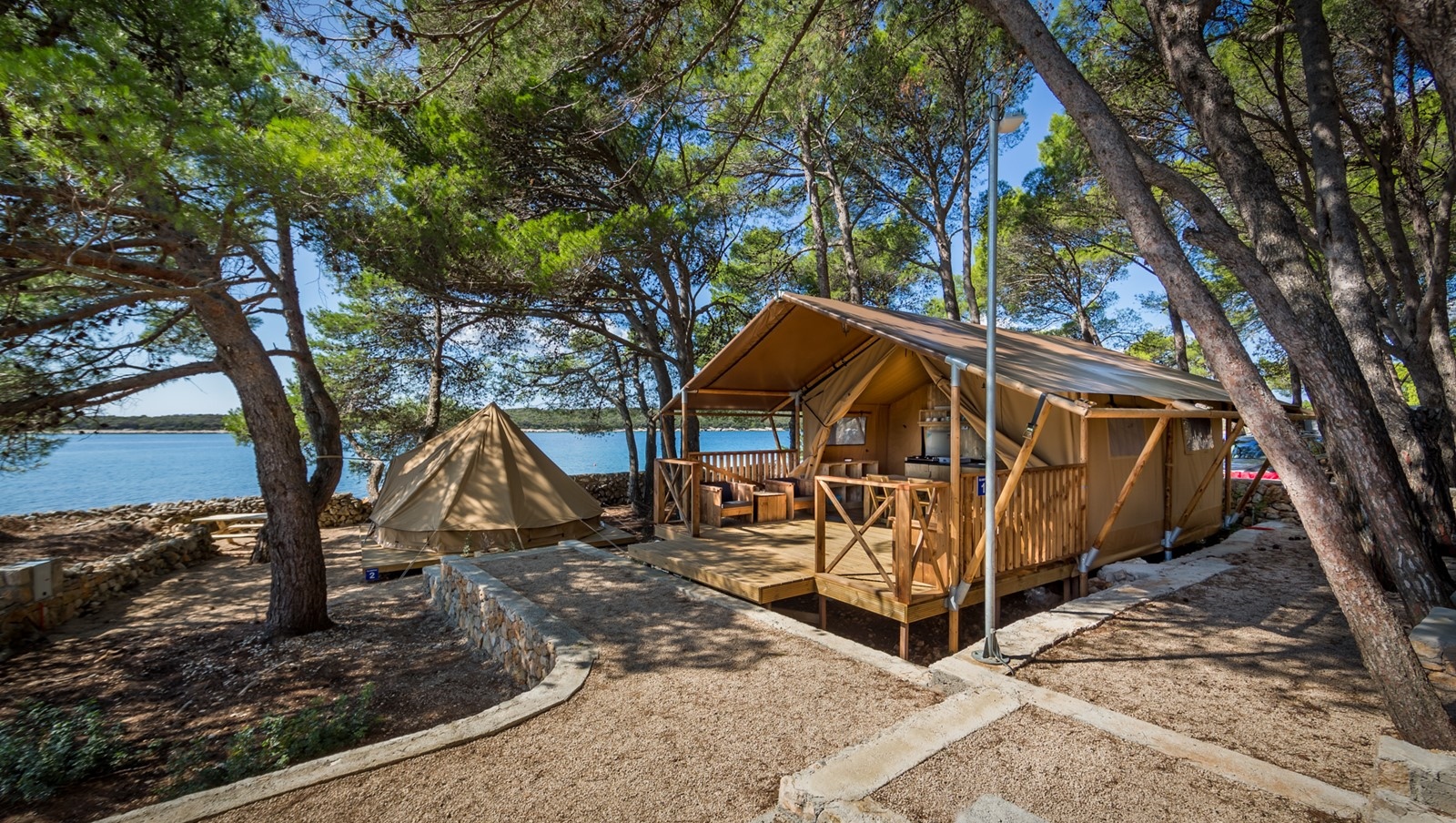 Tent and wooden cabin at Baldarin surrounded by trees near the water