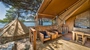 Outdoor glamping setup at Baldarin with wooden deck, tent, and seating area near the sea